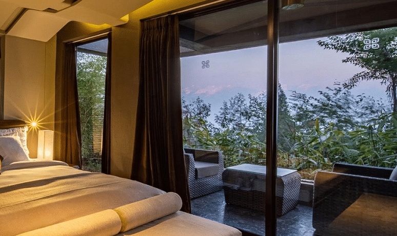 A bedroom with large window giving a view of a sitting area on the deck | Kavya Resort and Spa, Nagarkot